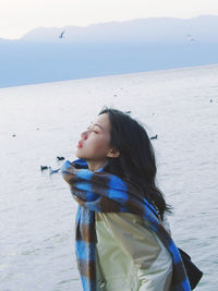 Side view of young woman sitting at beach