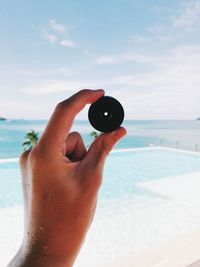 Close-up of hand holding equipment at beach against sky