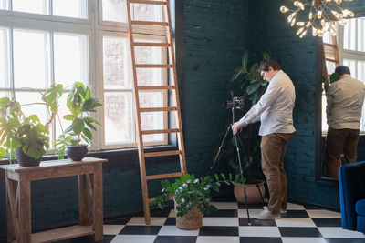 Male photographer working in stylish blue living room with plants