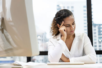 Young woman looking away while sitting on table