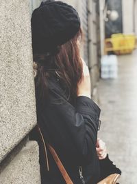Side view of woman leaning on concrete wall