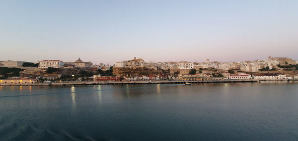 River and townscape against clear sky at dusk