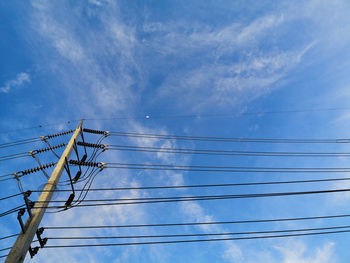 Low angle view of electricity pylon against blue sky