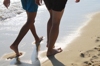 Low section of people walking on beach