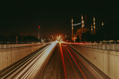 Light trails on road against sky at night