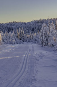 Snow covered landscape against clear sky during sunset