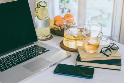 Morning time at home healthy breakfast laptop and drink on table. natural meal fruit, mobile phone 