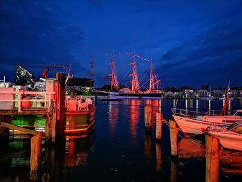 Sailboats moored in harbor against sky at night