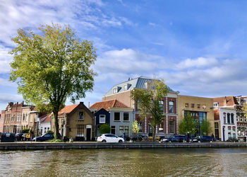 Houses by river against sky