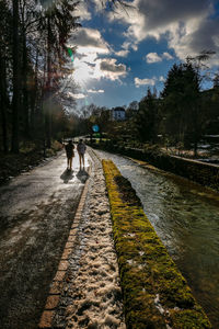 People walking on footpath by road against sky