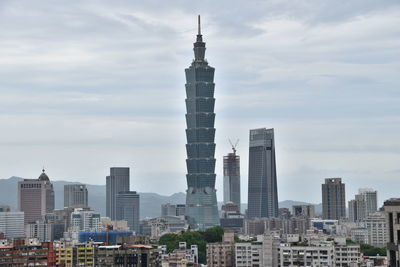 Buildings in city against cloudy sky