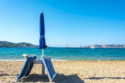 Blue parasol on beach against clear sky