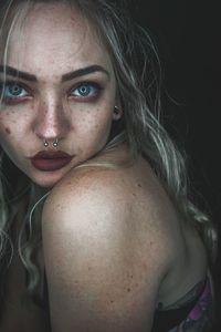 Close-up portrait of young woman with nose ring in darkroom