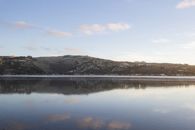 Scenic view of lake by mountains against sky