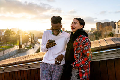 Young couple standing against sky in city