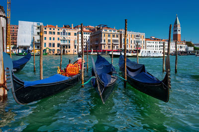 Boats moored in canal against buildings in city