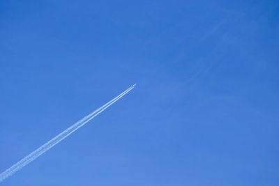 Low angle view of airplane flying against clear blue sky