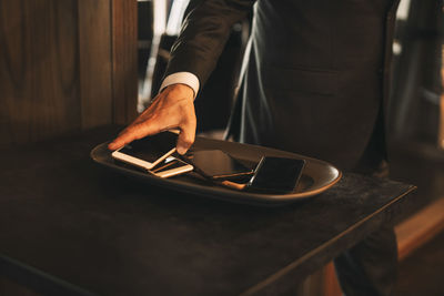 Midsection of male lawyer keeping smart phone on tray at office