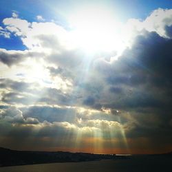 Sun shining through clouds over sea