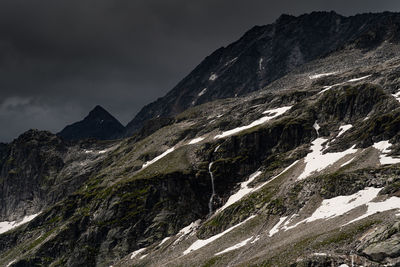 Scenic view of mountains against dark clouds 