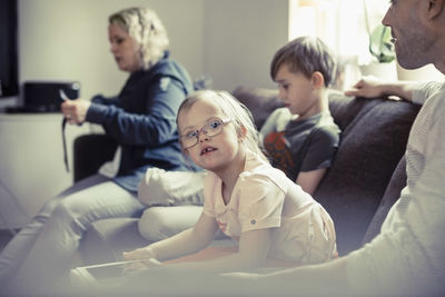 Portrait of handicapped girl sitting with family on sofa at home