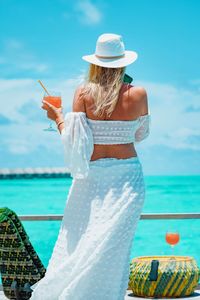 Rear view of woman wearing hat standing at beach