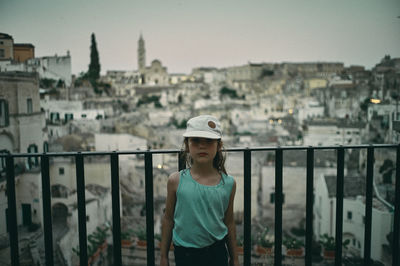 Portrait of young girl standing in front of old city