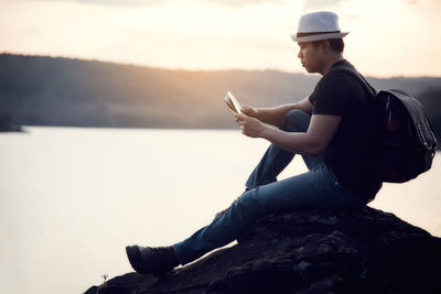 Side view of man using mobile phone against sky