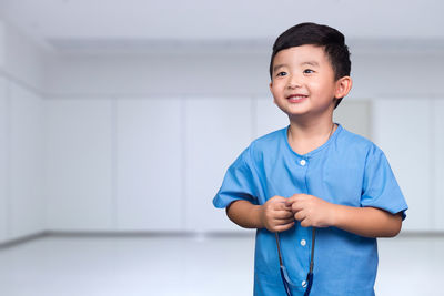Portrait of smiling boy standing against blue wall