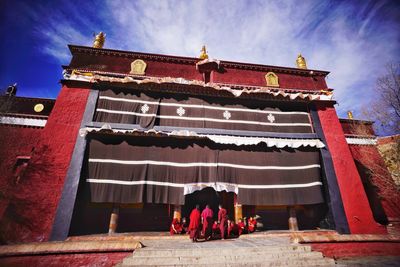 Low angle view of women standing on roof against sky