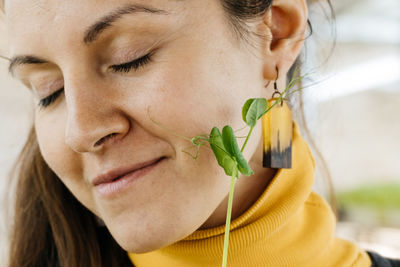 Happy woman eating freshly cut sprout of microgreen. close-up of young farmer trying her harvest