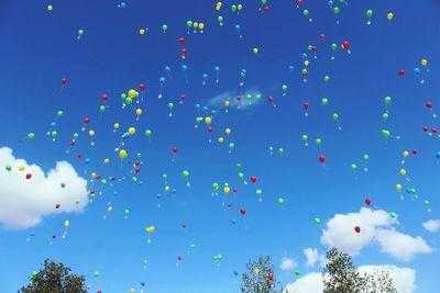 Low angle view of helium balloons against sky