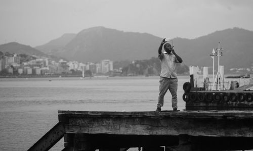 Rear view of man standing on mountain against sky
