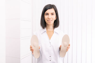 Happy woman with insoles standing against wall