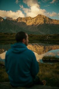 Rear view of man standing on mountain against sky