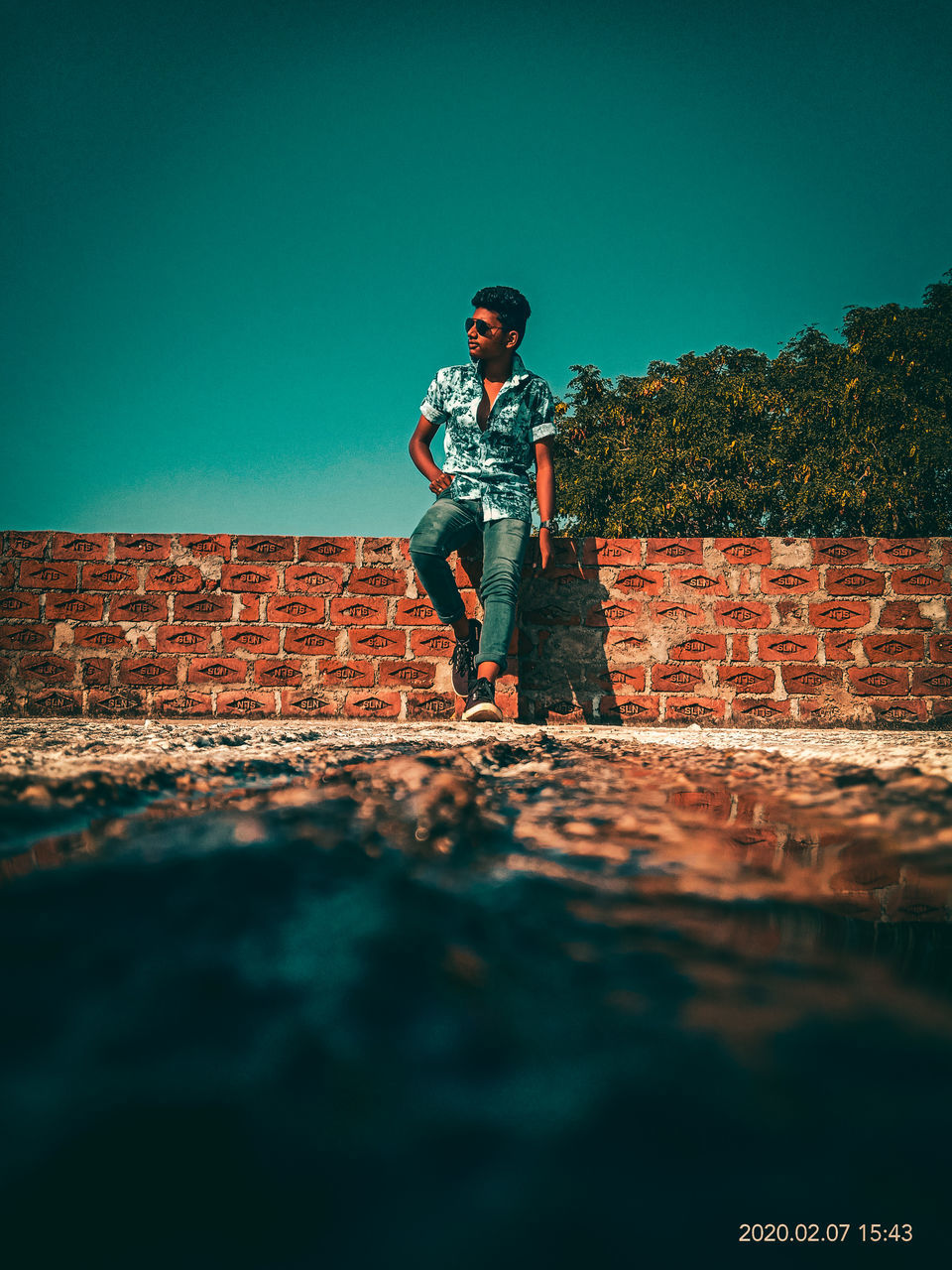 MAN STANDING ON WALL AGAINST CLEAR SKY