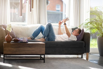 A woman is sitting on the couch reading a book