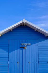 The front of a brightly coloured blue beach hut in eastbourne on a sunny summer's day