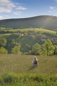 Woman in valley is showing something toward hills to her dog.