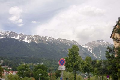 Road sign by trees against sky