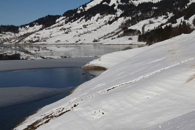 Scenic view of snowcapped mountains by lake during winter