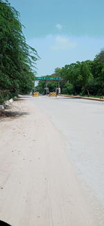 Empty road amidst trees in city against sky