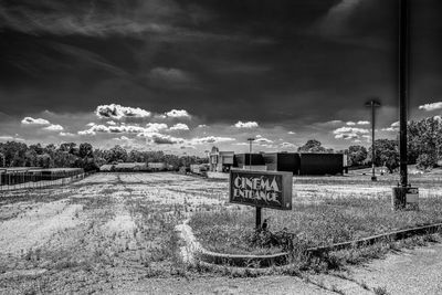 Road sign on field against sky