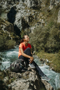 Woman sitting on rock at shore