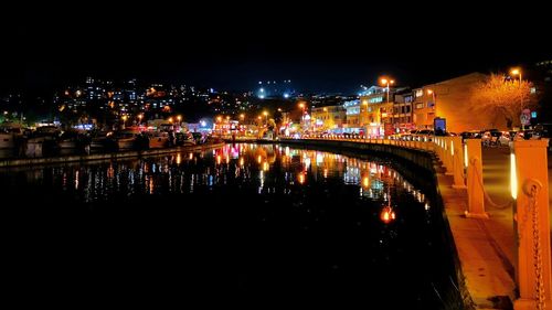 Illuminated buildings by river at night