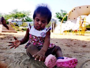 Full length of baby girl sitting on sand at playground
