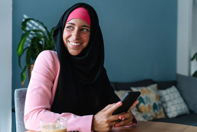 Portrait of smiling young woman using mobile phone