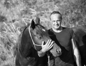 Portrait of smiling mature man standing by horse