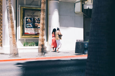 Rear view of women walking on street amidst buildings