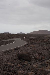 Road leading towards mountains against sky